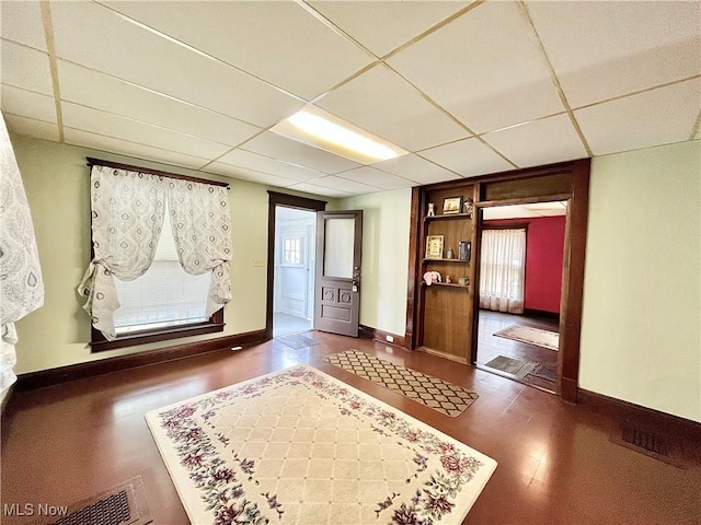 corridor featuring a paneled ceiling and dark wood-type flooring