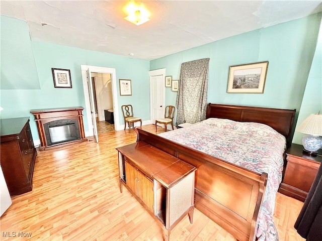 bedroom with light wood-type flooring, a fireplace, and a closet