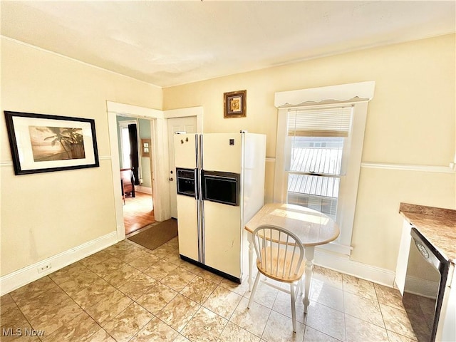 kitchen featuring stainless steel dishwasher and white refrigerator with ice dispenser