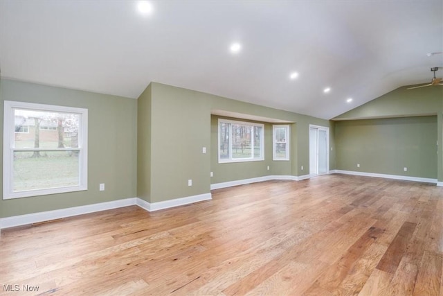 empty room with a healthy amount of sunlight, light hardwood / wood-style flooring, ceiling fan, and lofted ceiling