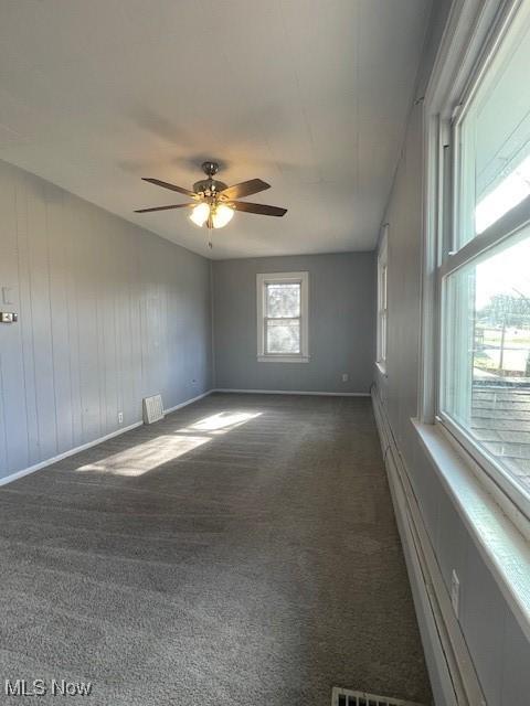 empty room with ceiling fan and dark carpet