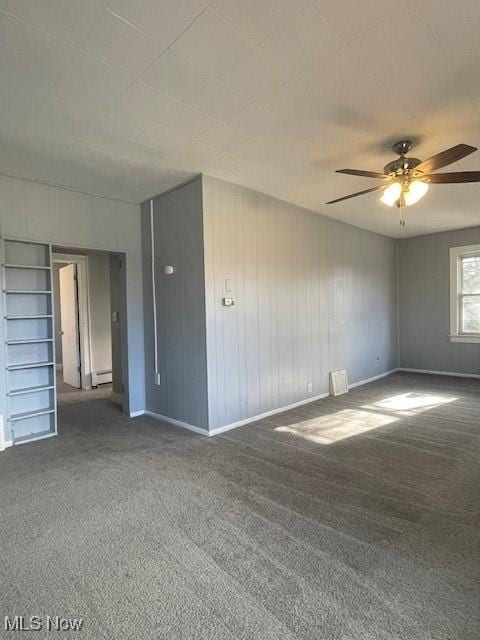 unfurnished room with ceiling fan, a baseboard heating unit, and dark colored carpet