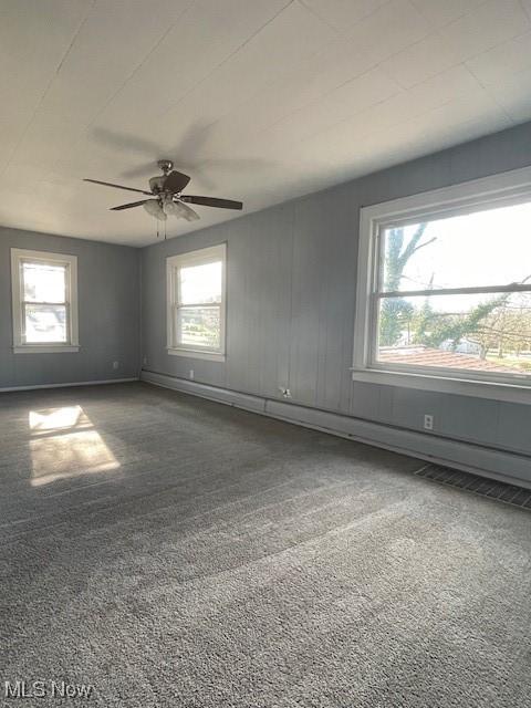 spare room with carpet flooring, ceiling fan, and a healthy amount of sunlight