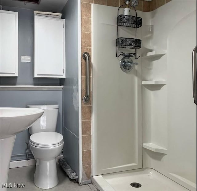 bathroom featuring tile patterned floors, toilet, and a shower