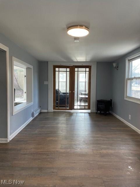 unfurnished living room featuring baseboard heating, french doors, and dark hardwood / wood-style floors