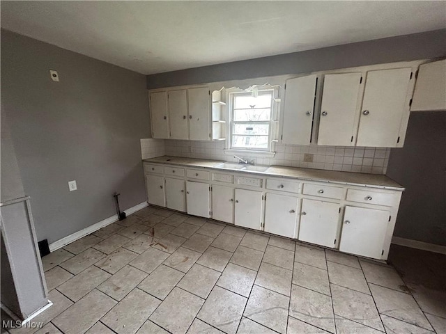 kitchen featuring white cabinets, sink, and tasteful backsplash