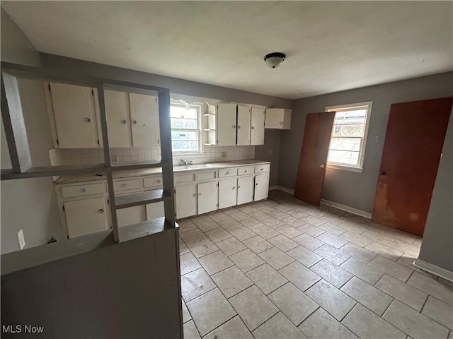 kitchen featuring decorative backsplash, white cabinets, a healthy amount of sunlight, and sink