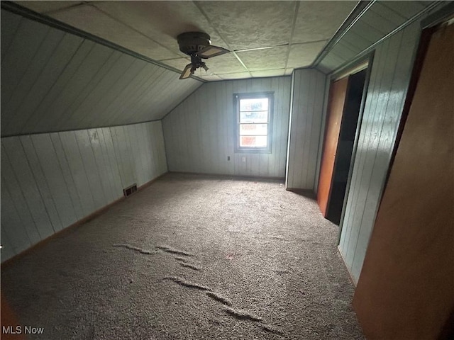 bonus room with ceiling fan, wood walls, light colored carpet, and lofted ceiling