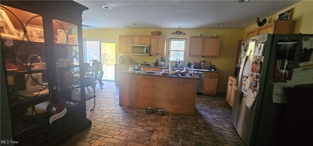 kitchen featuring light brown cabinetry, a kitchen island, stainless steel appliances, and sink