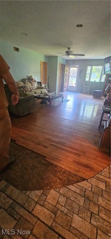 unfurnished living room featuring ceiling fan, a textured ceiling, and hardwood / wood-style flooring