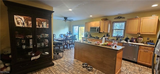 kitchen with ceiling fan, a kitchen island, sink, and stainless steel appliances