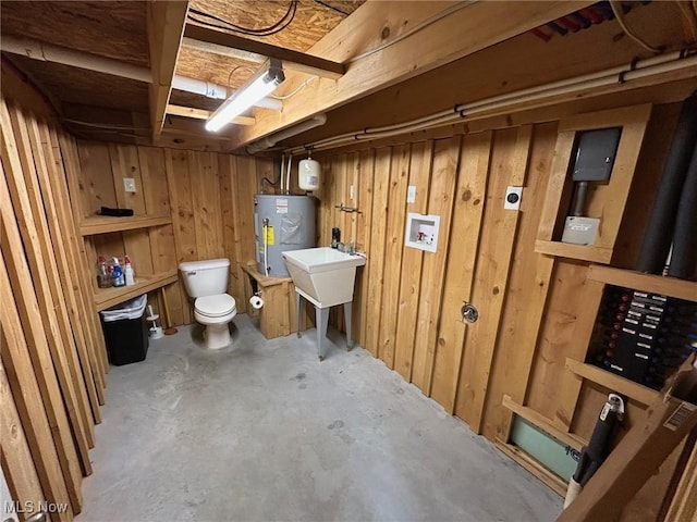 basement with electric water heater, sink, and wooden walls