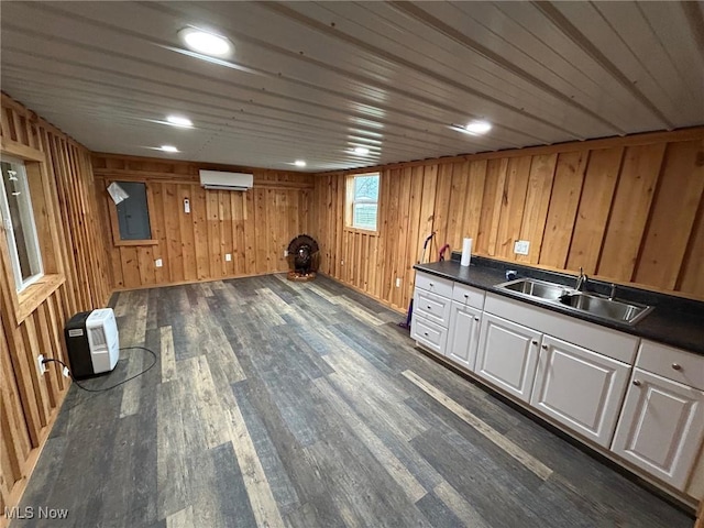 basement featuring a wall mounted air conditioner, dark hardwood / wood-style flooring, sink, electric panel, and wood walls