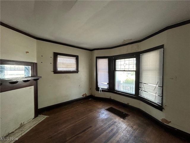 empty room with dark hardwood / wood-style flooring and crown molding