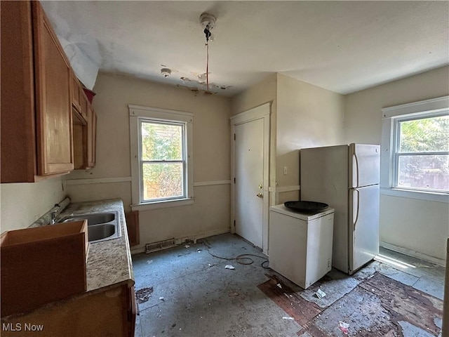 kitchen featuring plenty of natural light, white refrigerator, and sink