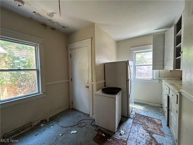 kitchen with white refrigerator and white cabinetry