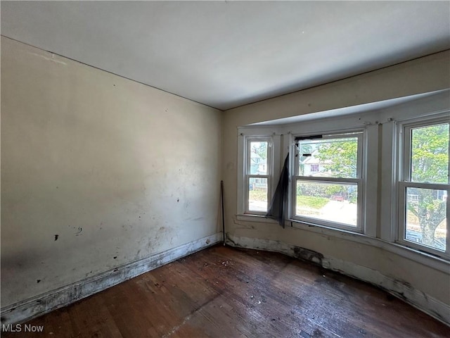 unfurnished room with dark hardwood / wood-style flooring and a wealth of natural light