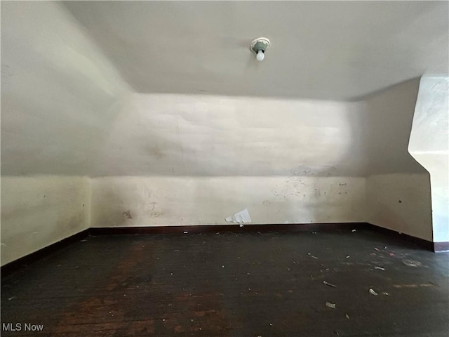 bonus room with lofted ceiling and dark wood-type flooring