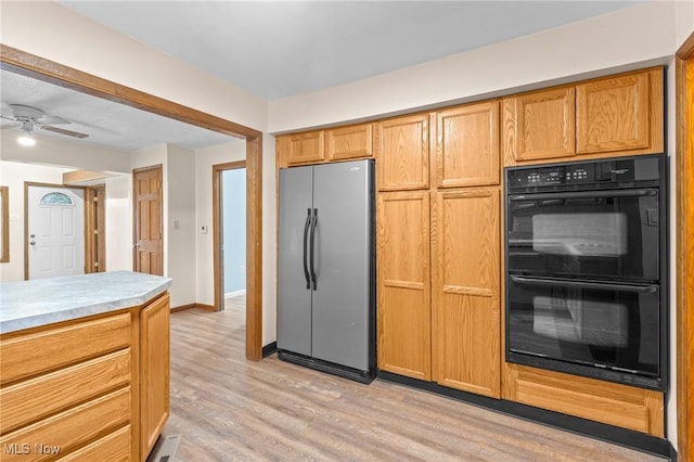 kitchen with double oven, stainless steel fridge, light hardwood / wood-style flooring, and ceiling fan