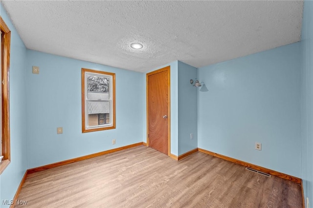 unfurnished bedroom featuring light hardwood / wood-style floors, a textured ceiling, and a closet