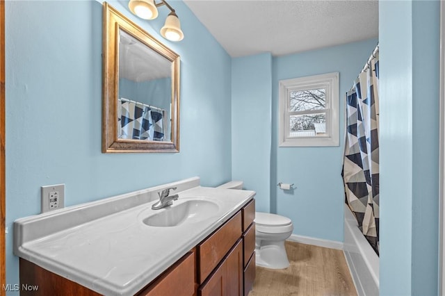 full bathroom with hardwood / wood-style floors, vanity, shower / bath combination with curtain, toilet, and a textured ceiling