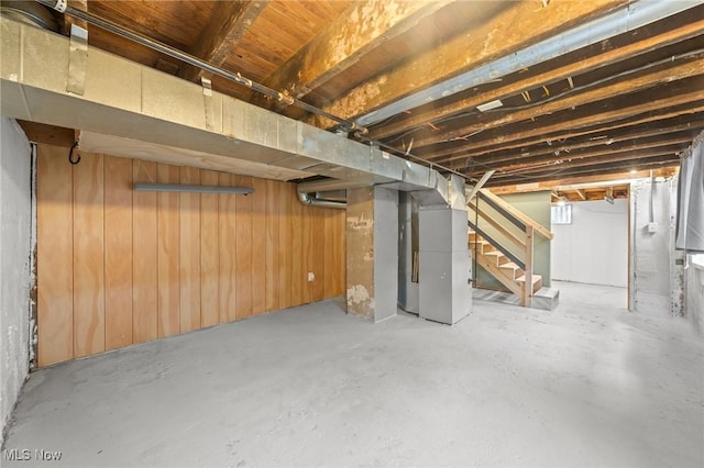 basement featuring heating unit and wood walls