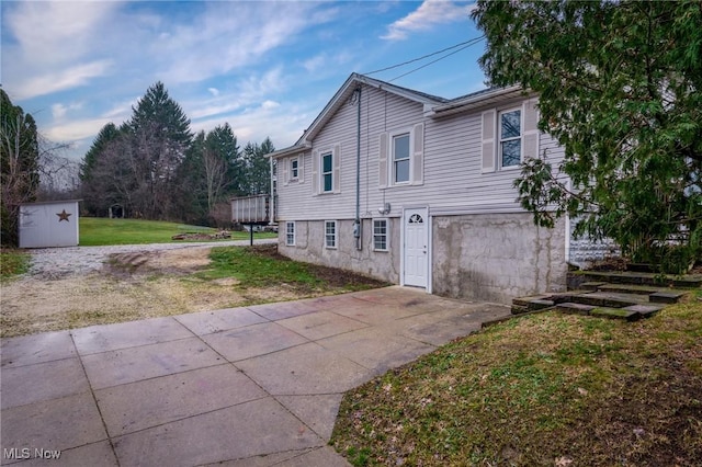 view of home's exterior featuring a deck, a storage unit, and a lawn