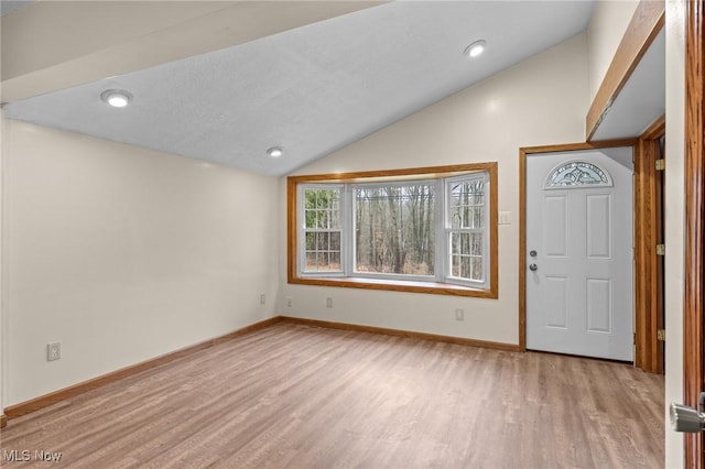 entryway with a textured ceiling, light hardwood / wood-style flooring, and lofted ceiling