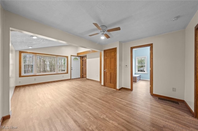 interior space with lofted ceiling, light hardwood / wood-style flooring, ceiling fan, and a textured ceiling