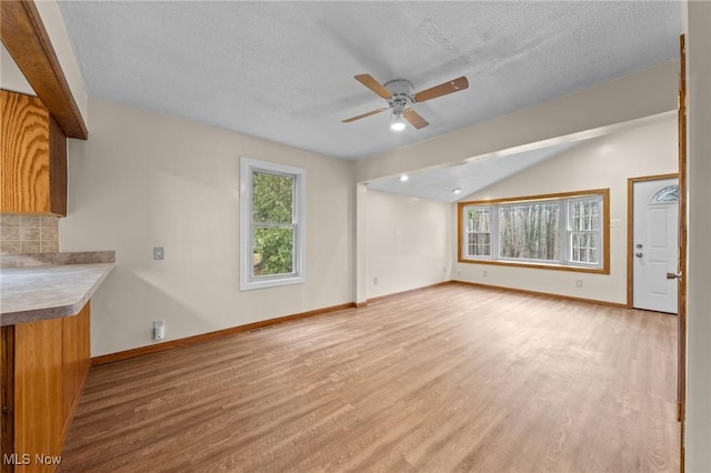 unfurnished living room with ceiling fan, a textured ceiling, and light wood-type flooring