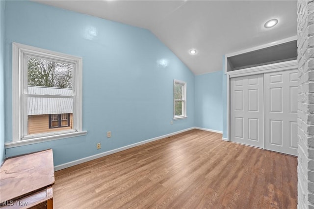 unfurnished bedroom featuring vaulted ceiling, light hardwood / wood-style flooring, and a closet