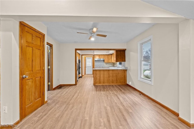 kitchen featuring kitchen peninsula, tasteful backsplash, ceiling fan, and light hardwood / wood-style floors