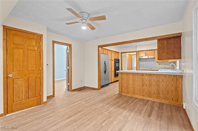 kitchen with double oven, stainless steel refrigerator, sink, and light hardwood / wood-style floors