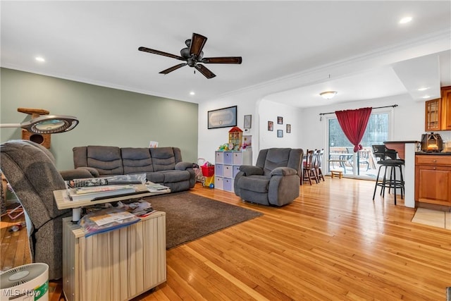 living room featuring ceiling fan, light hardwood / wood-style floors, and crown molding