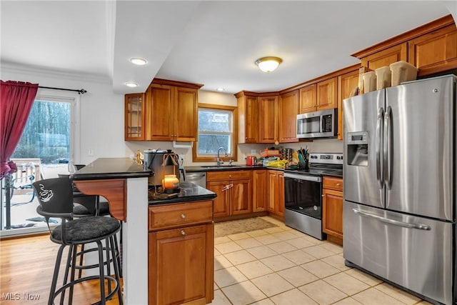 kitchen featuring a kitchen breakfast bar, sink, light tile patterned flooring, and appliances with stainless steel finishes