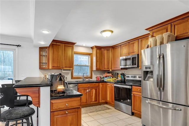 kitchen with a healthy amount of sunlight, sink, stainless steel appliances, and a breakfast bar area