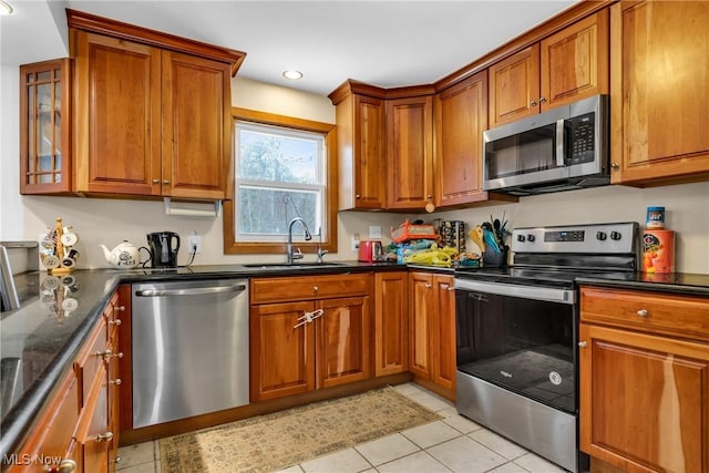 kitchen with light tile patterned floors, stainless steel appliances, dark stone counters, and sink