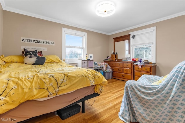 bedroom featuring multiple windows, light hardwood / wood-style flooring, and ornamental molding