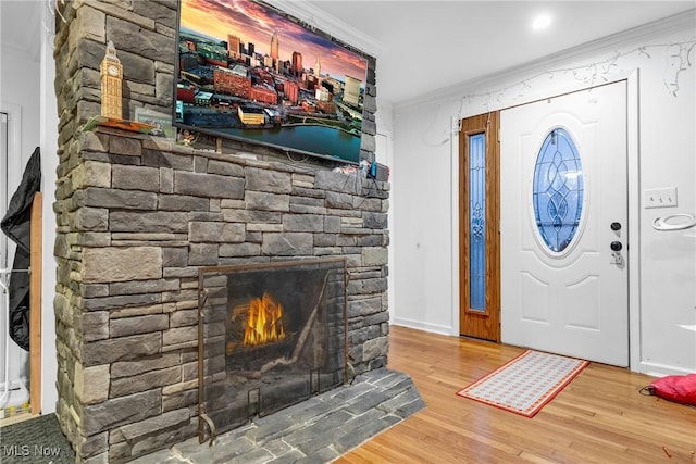 entryway with crown molding, a fireplace, and hardwood / wood-style flooring