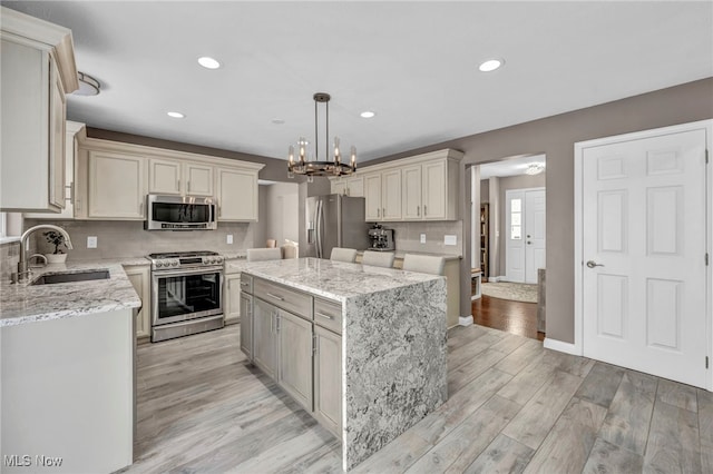 kitchen with pendant lighting, a center island, sink, light wood-type flooring, and stainless steel appliances