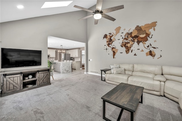 carpeted living room featuring ceiling fan with notable chandelier and high vaulted ceiling