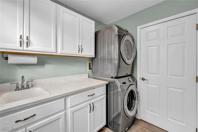 washroom with cabinets, light hardwood / wood-style flooring, stacked washer and clothes dryer, and sink