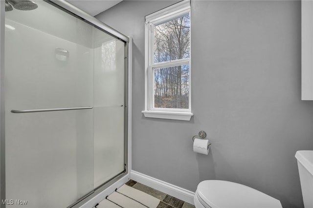 bathroom featuring toilet and a shower with shower door