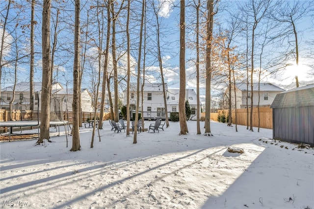 yard layered in snow with a trampoline