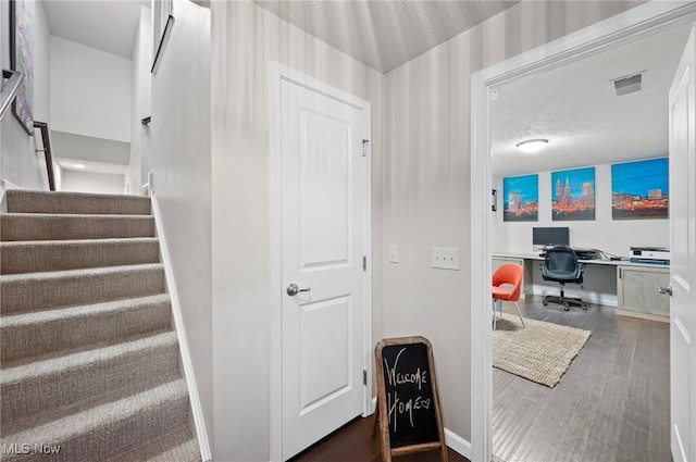 stairs with wood-type flooring, a textured ceiling, and built in desk