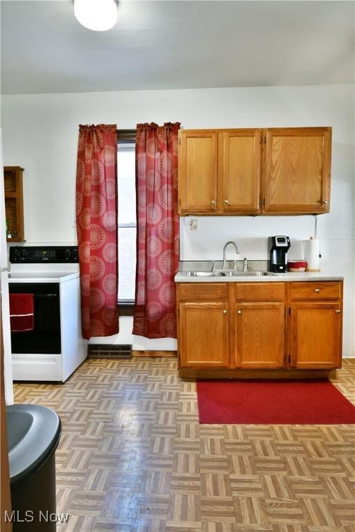 kitchen with light parquet flooring, white range with electric cooktop, and sink