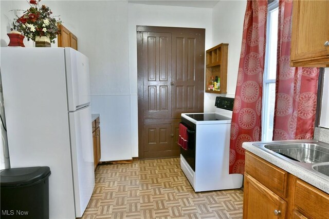 kitchen featuring white appliances and light parquet floors