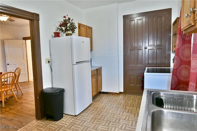 kitchen featuring ceiling fan, white refrigerator, and sink