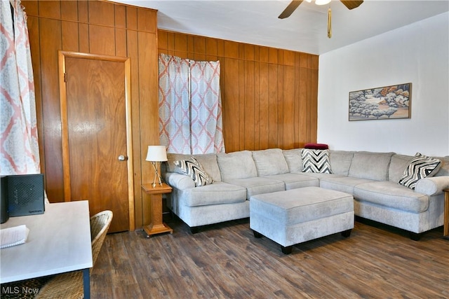 living room with dark hardwood / wood-style flooring, ceiling fan, and wood walls