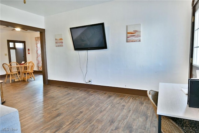 living room featuring ceiling fan and dark wood-type flooring